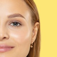Caucasian young woman's close up shot on yellow studio background. Beautiful female model with perfect well-kept skin. Concept of human emotions, facial expression, beauty, healthy lifestyle.